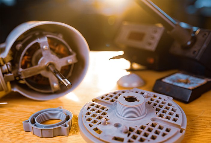 Pièces de rechange imprimées en 3D pour un moteur ou appareil électronique, posées sur un établi en bois